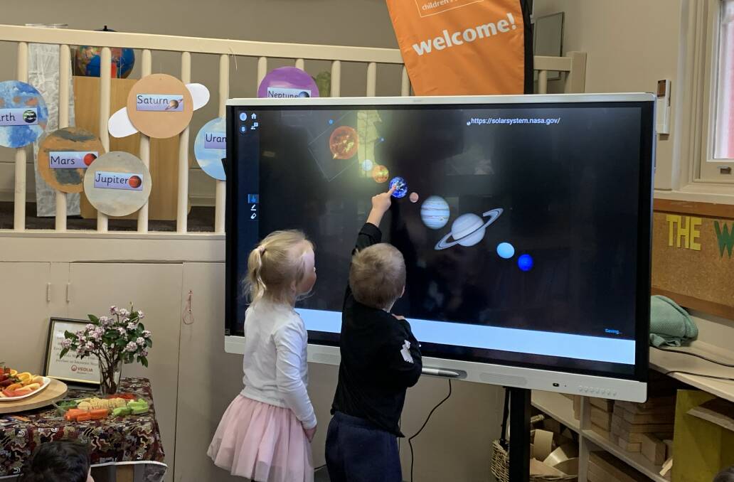 Mia Skelly and James Bain demonstrating the use of the interactive smart board as they look through the planets.