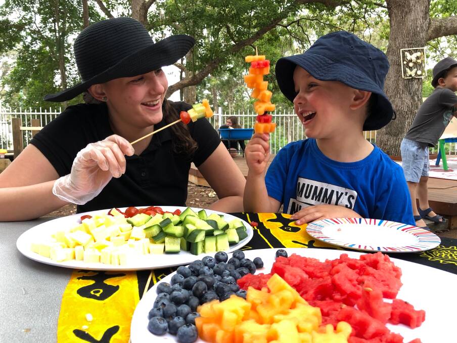 TAFE NSW Certificate III Early Childhood Education and Care student Layla Stamatis helps Marcus Bolton find healthy fun in fruit on sticks. Photo: Supplied.