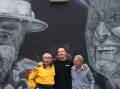 Kiama street artist Samuel Hall with his latest mural and the two volunteer firefighters, Brian Coates and John Matters, who were the subject of the artwork. Picture by Erin Olafson