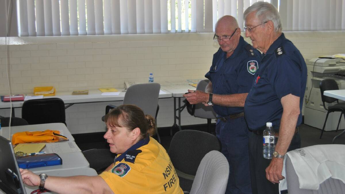 WATCHING: RFS community liaison officer Peter Dyce, John Sendall, also from the RFS, monitored the progress of Yass fires with RFS planning officer Cherie Roach at the Southern Tablelands control centre in Goulburn this afternoon. Photo: Antony Dubber. 